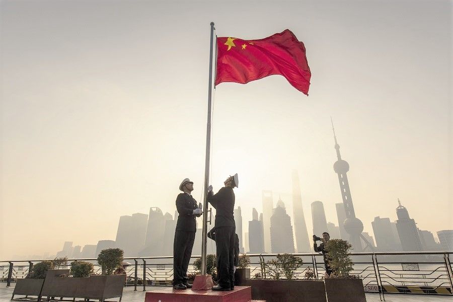 China Customs officers raise a Chinese flag during a rehearsal for a flag-raising ceremony along the Bund past buildings in the Lujiazui Financial District at sunrise in Shanghai, China, on 4 January 2022. (Qilai Shen/Bloomberg)