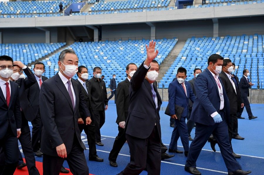 Cambodian Prime Minister Hun Sen waves next to China's State Councilor and Foreign Minister Wang Yi as they attend a handover ceremony at the Morodok Techo National Stadium, which will be the main venue for Cambodia's 2023 SEA Games, in Phnom Penh, Cambodia, 12 September 2021. (Tang Chhin Sothy/Pool via Reuters)