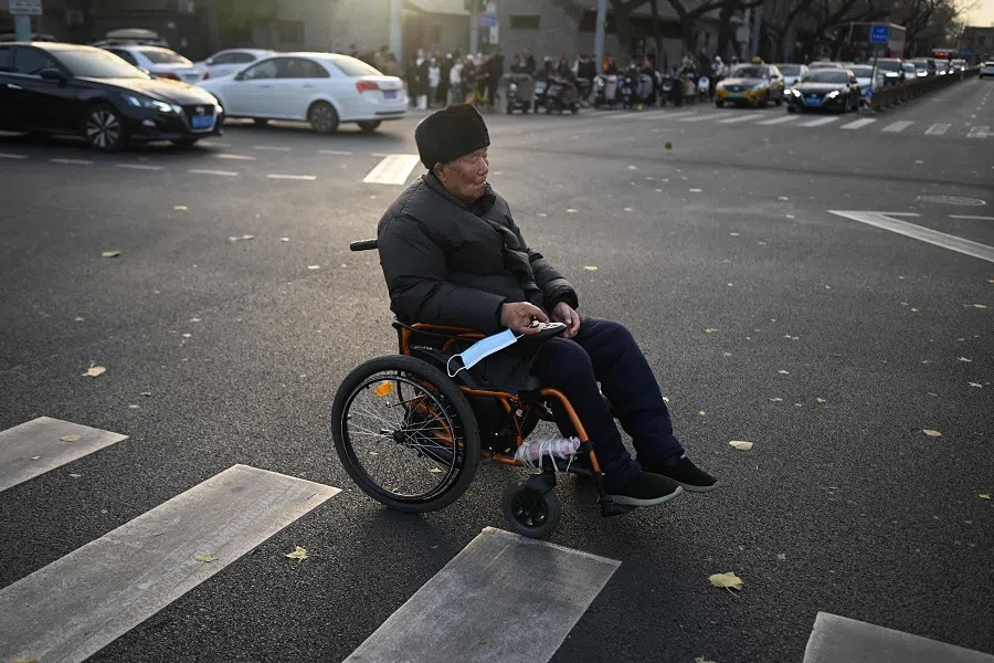 An elderly man on an electric wheelchair crosses a street in Beijing, China, on 22 November 2023. (Wang Zhao/AFP)