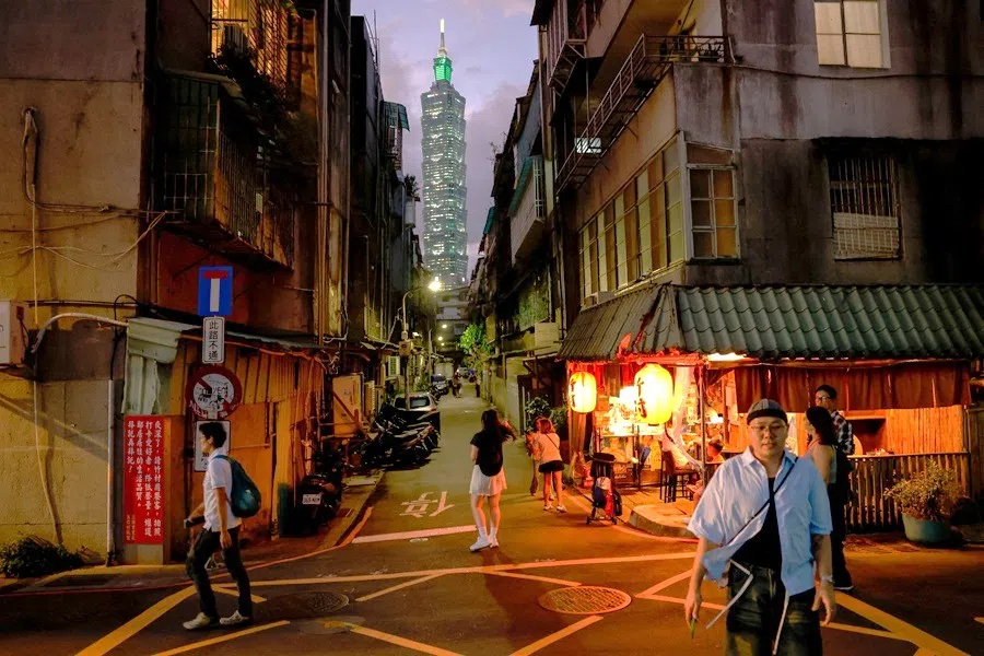 People walk as the Taipei 101 building is seen in the distance, in Taipei, Taiwan, on 9 October 2025.