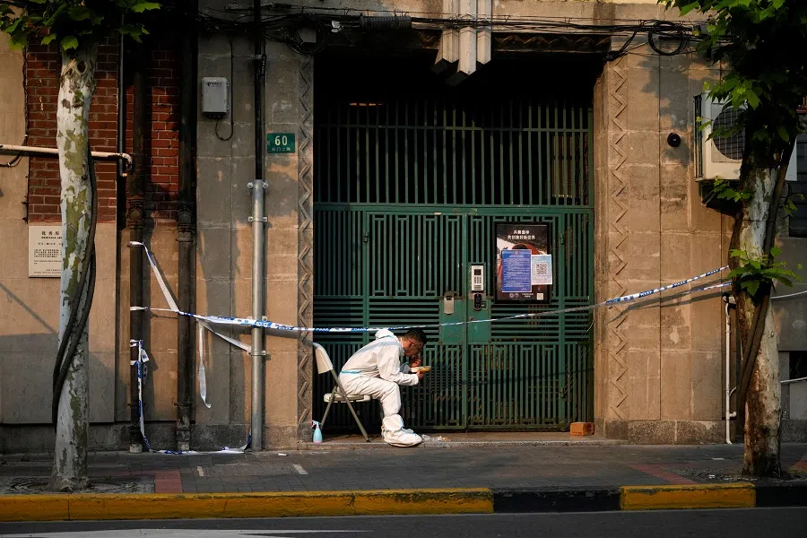 A worker in a protective suit eats dinner at a closed residential area during lockdown, amid the Covid-19 pandemic, in Shanghai, China, 16 May 2022. (Aly Song/Reuters)