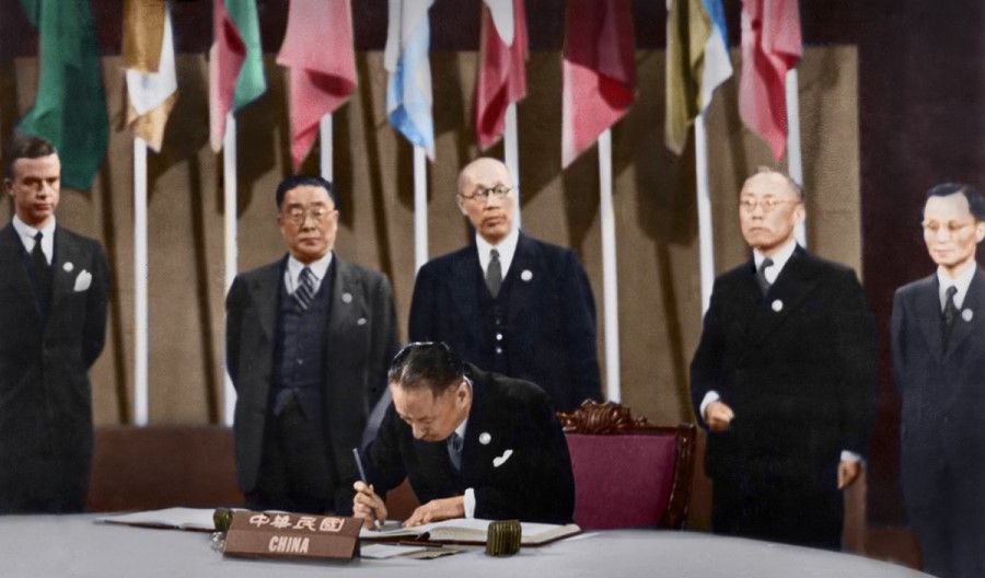 26 June 1945, San Francisco - At the UNCIO meeting, V.K. Wellington Koo, ambassador of the Republic of China (ROC) and chief delegate of the ROC delegation, is signing the UN Charter. Standing behind him (from left) are Alger Hiss, executive secretary of the conference; Hu Lin, editor-in-chief of the Ta Kung Pao; Dong Biwu, representative of the Chinese Communist Party, Chang Chun-mai (Zhang Junmai), representative of the China Democratic Socialist Party; and Li Huang, representative of the China Youth Party.