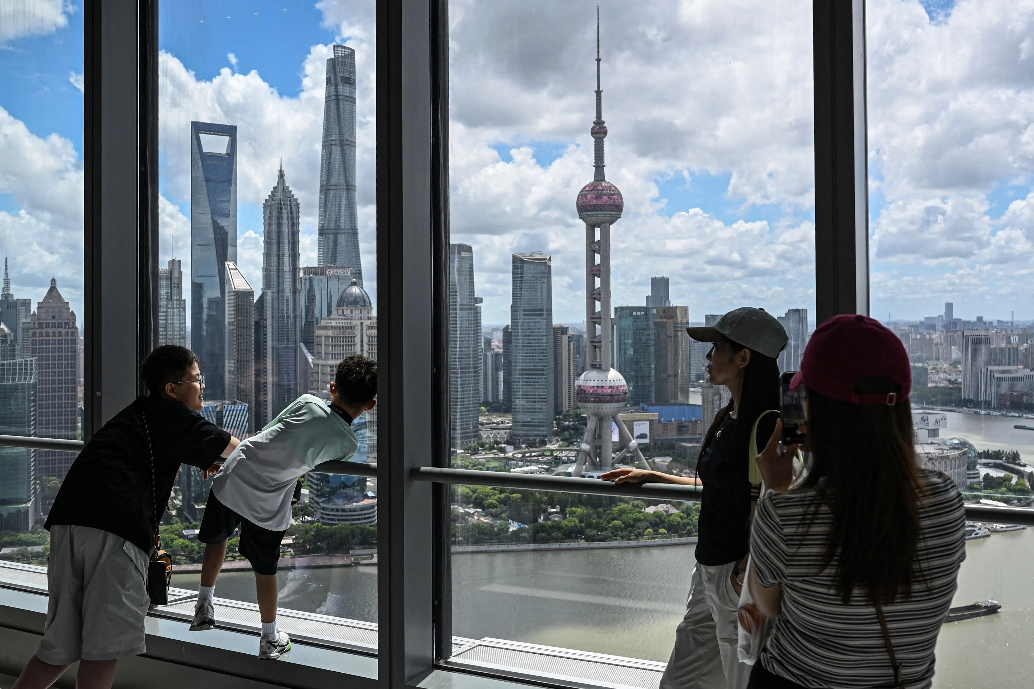 People take in the view of the city’s skyline from a coffee shop in Shanghai on 24 August 2026.