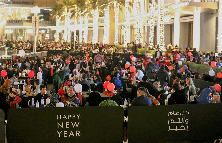 People gather outside the Burj Khalifa as they wait for fireworks on New Year's Eve, in Dubai, United Arab Emirates, 31 December 2022. (Satish Kumar/Reuters)
