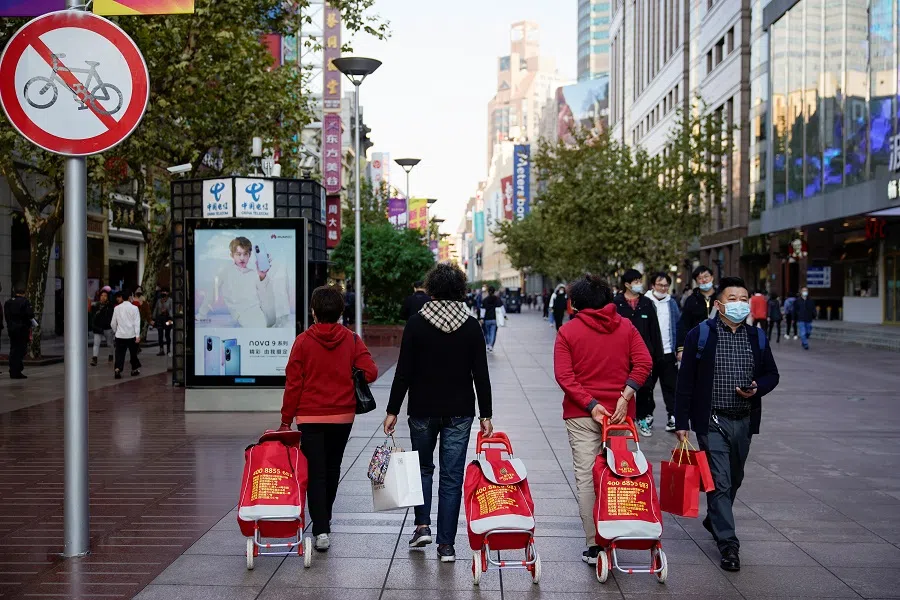 People walk with their shopping carts at a main shopping area during the Singles' Day shopping festival in Shanghai, China, 11 November 2021. (Aly Song/Reuters)