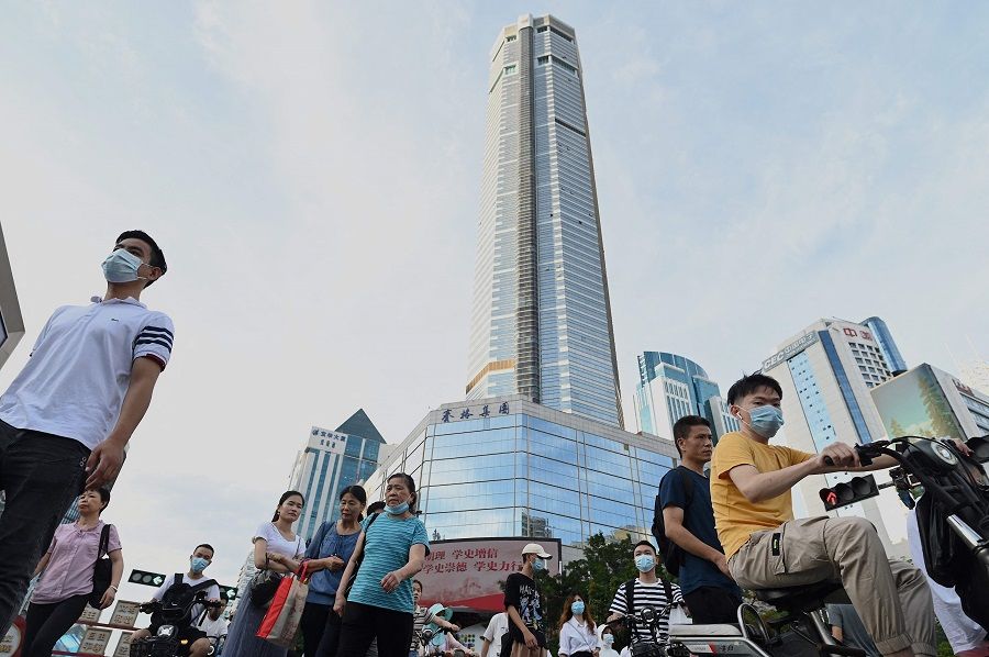 This file photo taken on 24 May 2021 shows people walking past the temporarily closed of 300 metre SEG Plaza (centre) in Shenzhen, Guangdong province, China. (Noel Celis/AFP)