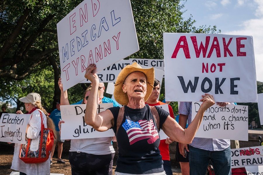 Counter demonstrators hold up signs outside of the Texas State Capitol during the Georgetown to Austin March for Democracy rally on 31 July 2021 in Austin, Texas, US. (Brandon Bell/Getty Images/AFP)