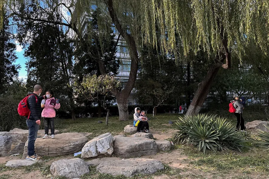 People carrying children rest outside a children's hospital in Beijing, China, on 27 November 2023. (Tingshu Wang/Reuters)