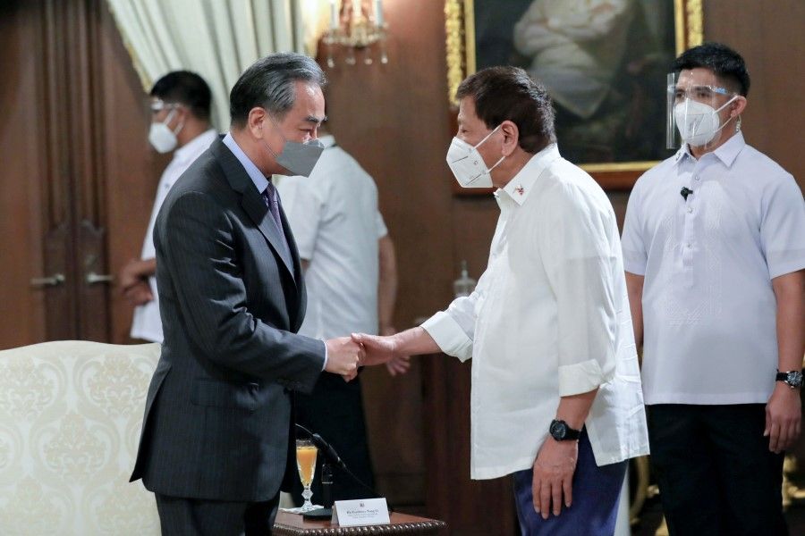 This handout photo taken on 16 January 2021 and received from the Presidential Photo Department (PPD) shows Philippine President Rodrigo Duterte (second from right) welcoming China's Foreign Minister Wang Yi (left) during a courtesy call at the Malacanang Palace in Manila. (Richard Madelo/Presidential Photo Department/AFP)