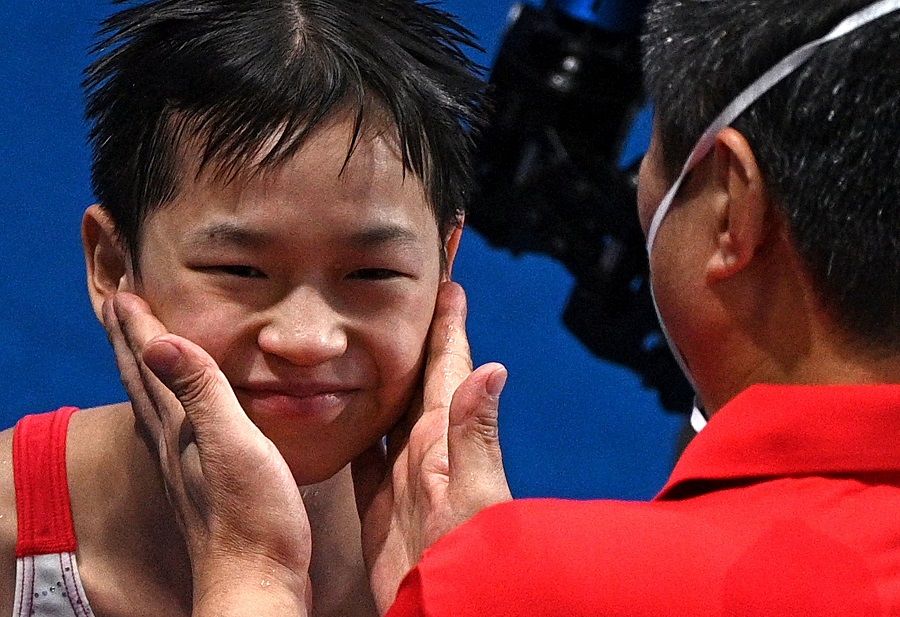 China's Quan Hongchan is congratulated by a coach after winning the women's 10m platform diving finals event during the Tokyo 2020 Olympic Games at the Tokyo Aquatics Centre in Tokyo, Japan on 5 August 2021. (Oli Scarff/AFP)
