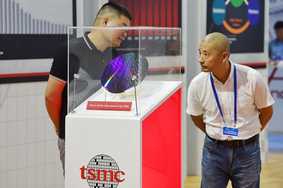 A man watches a 300mm wafer manufactured by Taiwan Semiconductor Manufacturing Company (TSMC) during the World Semiconductor Congress in Nanjing, Jiangsu province, China, on 19 July 2023. (AFP)