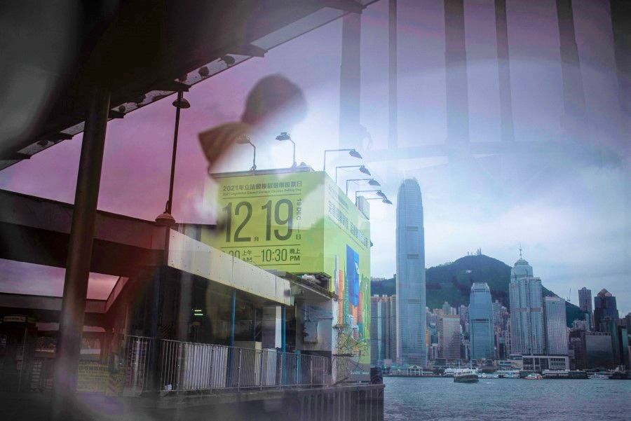 A government banner of the upcoming Legislative Council election is seen through a reflection in Hong Kong on 22 November 2021. (Louise Delmotte/AFP)