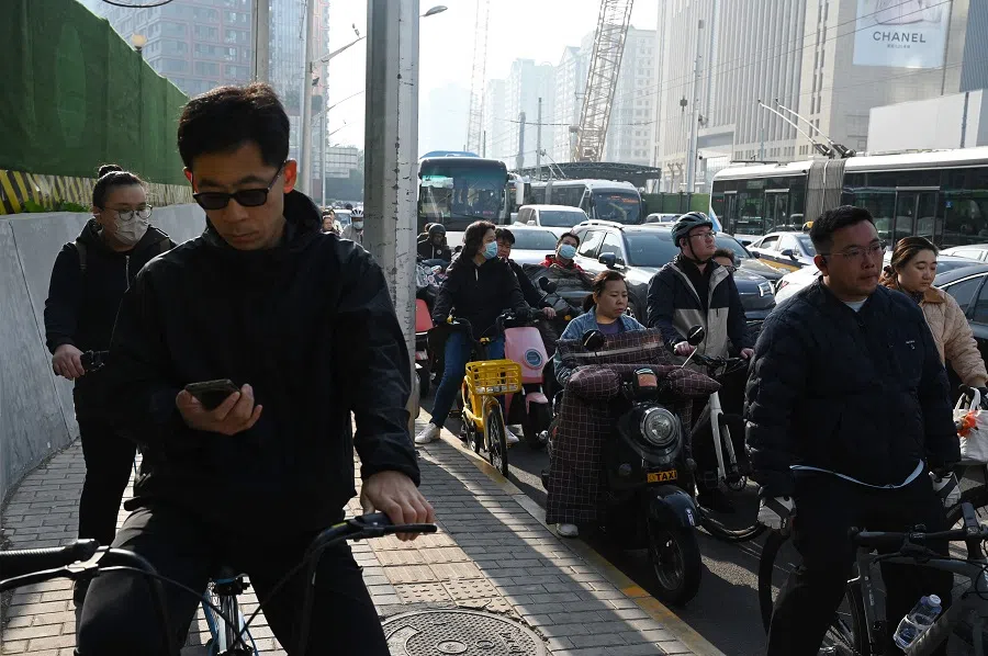 People wait to cross a road in Beijing’s central business district on 10 April 2025.