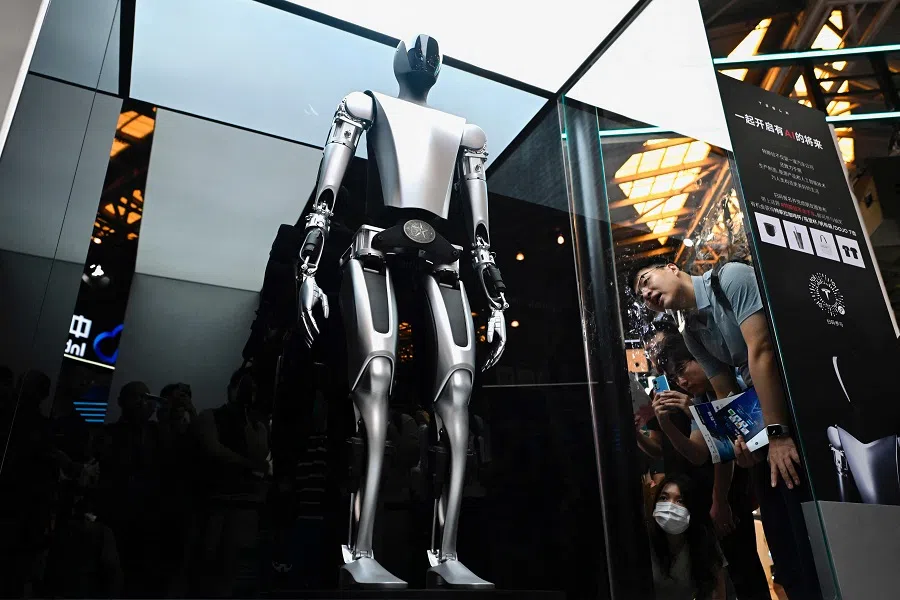 Visitors watch a Tesla robot displayed at the World Artificial Intelligence Conference in Shanghai, China, on 6 July 2023. (Wang Zhao/AFP)