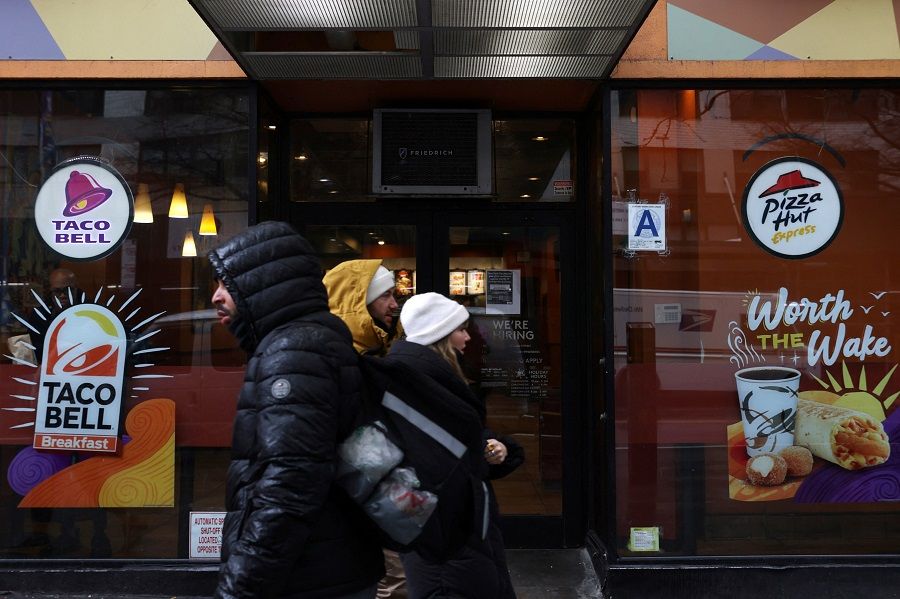 People walk by a Taco Bell and Pizza Hut in Manhattan, New York City, US, 7 February 2022. (Andrew Kelly/Reuters)