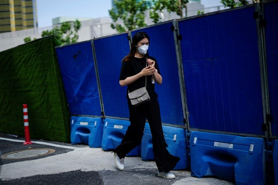 A woman wearing a protective face mask walks on a street, after the lockdown placed to curb the Covid-19 outbreak was lifted in Shanghai, China, 8 June 2022. (Aly Song/Reuters)