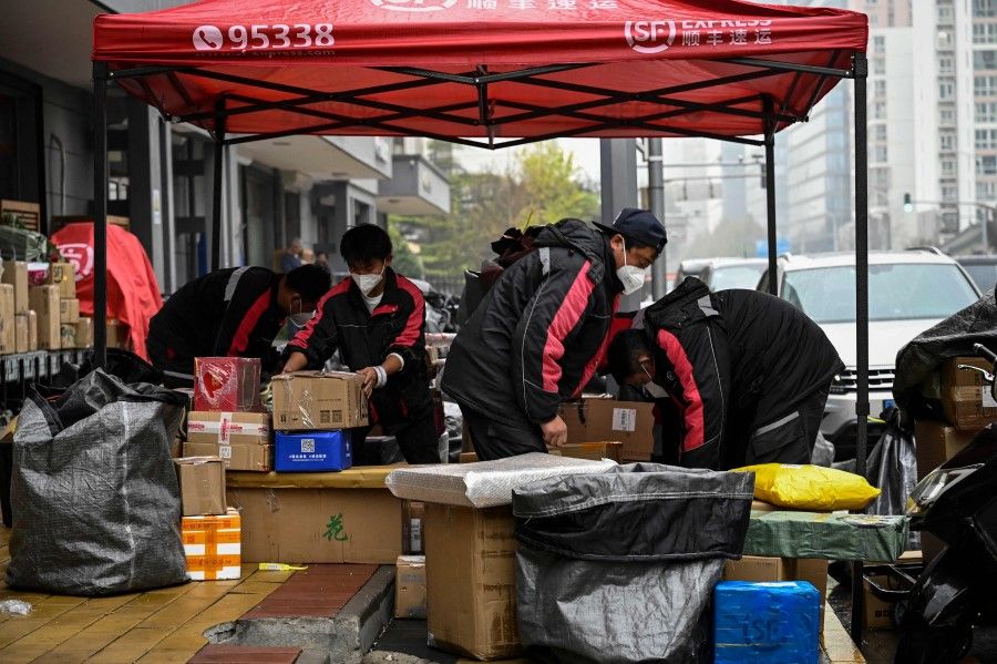 Delivery workers sort packages to be delivered to customers on "Singles' Day", also known as the Double 11, along a street in Beijing on 11 November 2022. (Jade Gao/AFP)