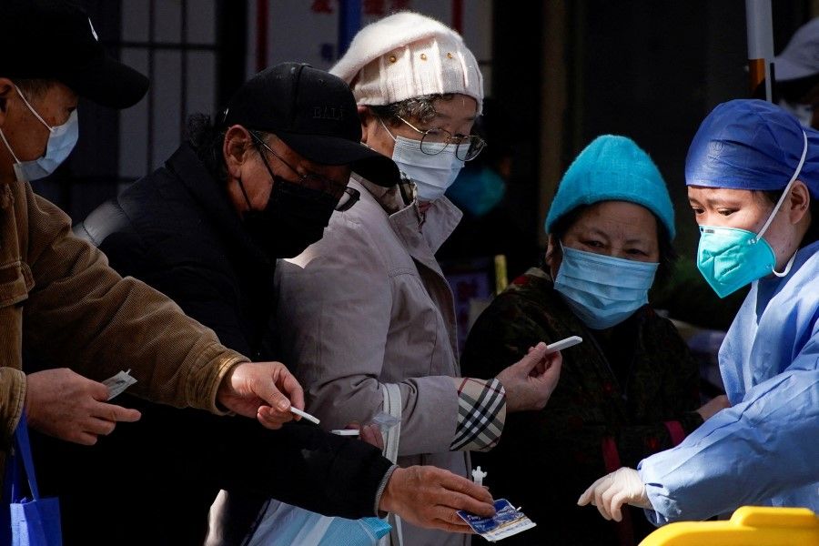 A medical worker in a protective suit checks rapid antigen tests for Covid-19 at an entrance of a hospital, as coronavirus disease (Covid-19) outbreaks continue in Shanghai, China, 13 December 2022. (Aly Song/Reuters)