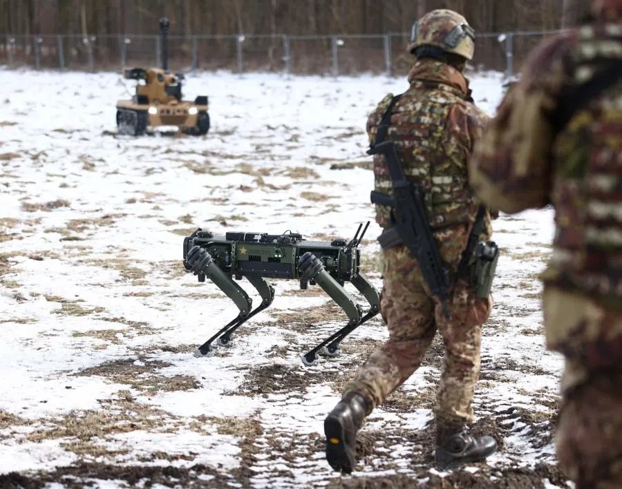 Soldiers walk next to a Veco Robotics “robot dog” Q-UGV “Cesare” and an unmanned ground vehicle “ASLAN” during the NATO exercise STEADFAST DART 26 in Bergen, Germany, on 19 February 2026. (Liesa Johannssen/Reuters)