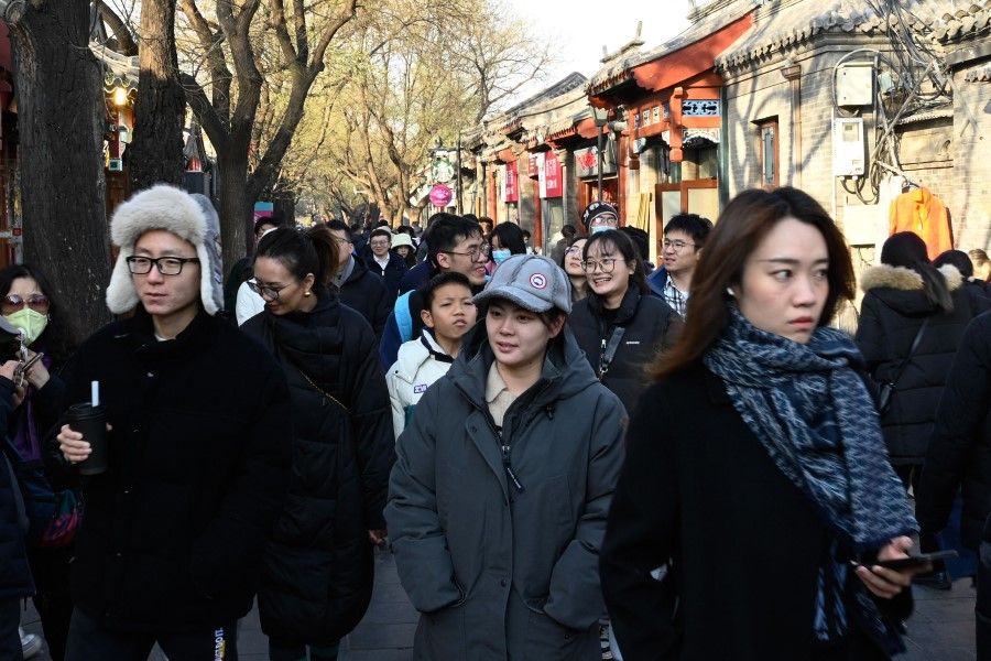 People walk along a street in the Dongcheng district of Beijing on 3 December 2023. (Pedro Pardo/AFP)