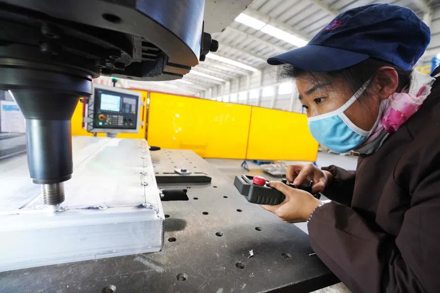 A worker at a machine as it welds aluminium at a factory in Zouping, in China's Shandong province. China's industrial production, retail sales and investment all contracted in the first two months of the year, following the coronavirus epidemic. (STR/AFP)