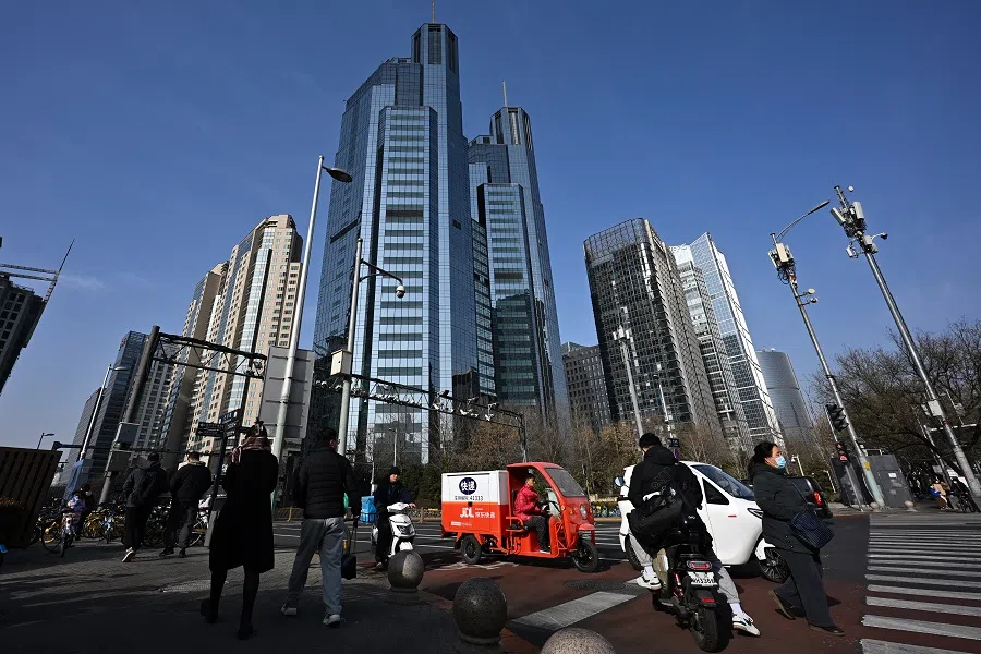 Pedestrians crossing the road in front of office and commercial buildings in the central business district of China's capital Beijing, on 9 December 2023. (SPH Media)
