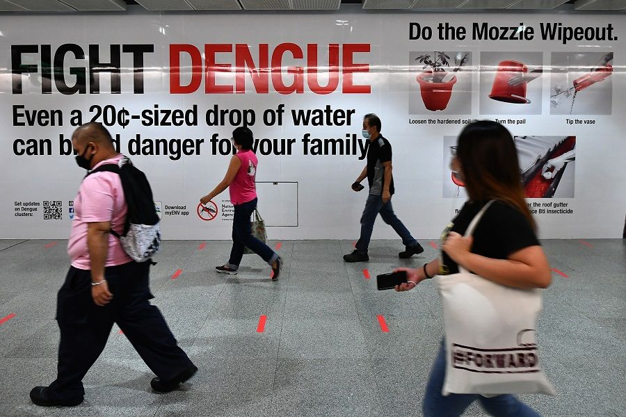 Commuters walk past a Fight Dengue banner at an MRT station in Singapore on 15 May 2020. (SPH Media)