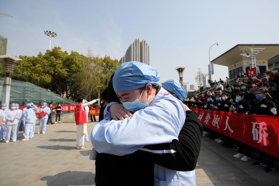 A local medical worker embraces and bids farewell to a medical worker from Jiangsu at the Wuhan Railway Station as the medical team from Jiangsu leaves Wuhan, 19 March 2020. (China Daily via REUTERS)