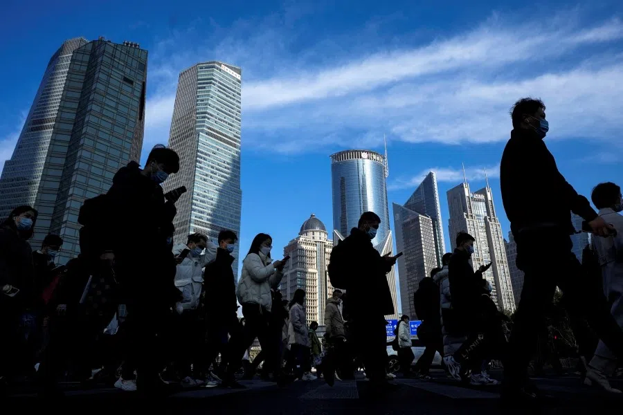 People cross a street near office towers in the Lujiazui financial district in Shanghai, China, 28 February 2023. (Aly Song/Reuters)