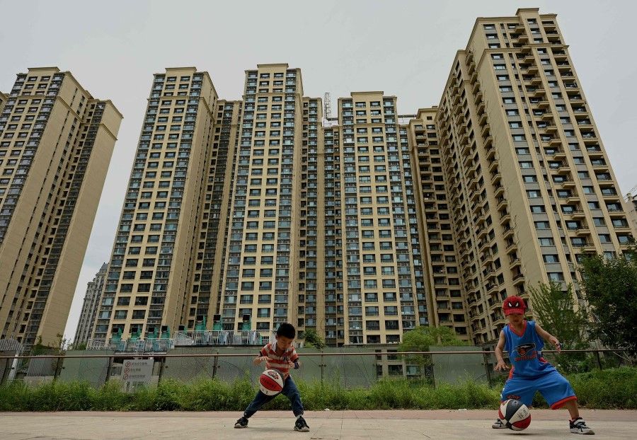 This file photo taken on 28 July 2022 shows children playing basketball in front of a housing complex constructed by Chinese property developer Evergrande in Beijing. (Noel Celis/AFP)