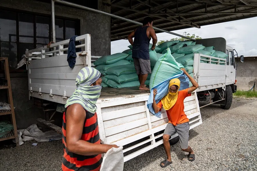 Workers unload sacks of chicken feed from a truck at a poultry farm in Pampanga province, Philippines, on 6 August 2024. (Lisa Marie David/Bloomberg)