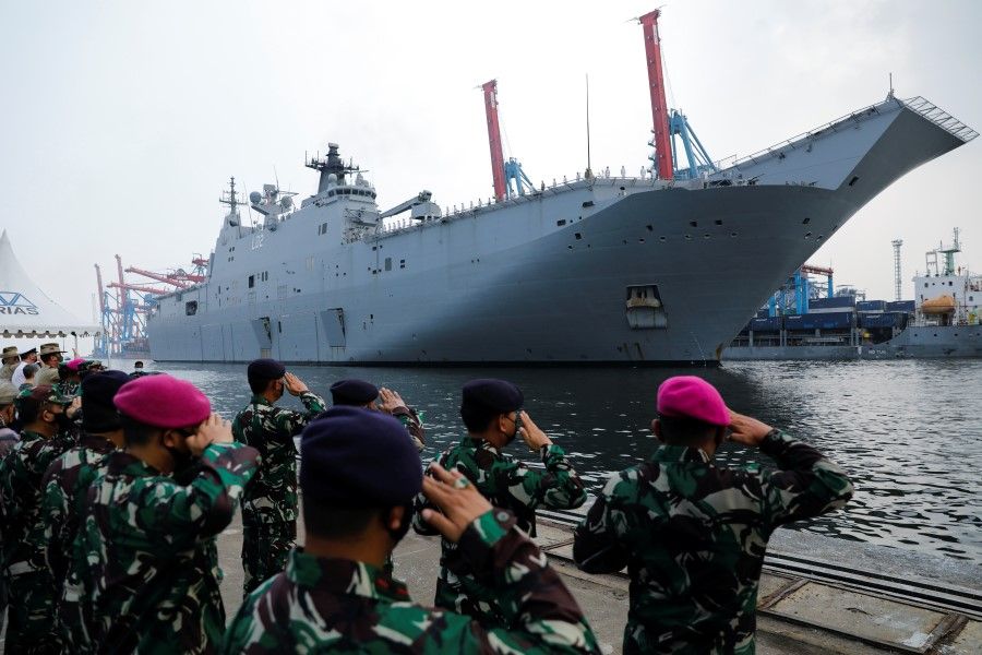 Indonesian Navy officers salute to welcome the Landing Helicopter Dock (LHD) ship, HMAS Canberra, that arrived at the Tanjung Priok port as part of Indo-Pacific Endeavour 2021, in Jakarta, Indonesia, 25 October 2021. (Willy Kurniawan/Reuters)
