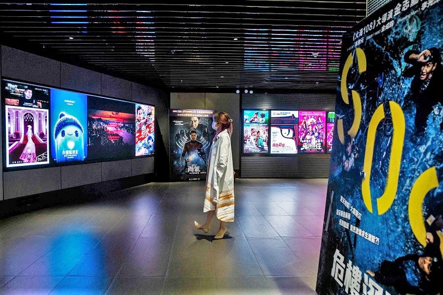 This picture taken on 2 September 2021 shows a women looking at movie advertisements at a cinema in Hong Kong. (Isaac Lawrence/AFP)