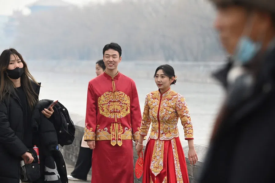 A couple waits during a wedding photo shoot outside the Forbidden City in Beijing on 11 February 2025. (Greg Baker/AFP)