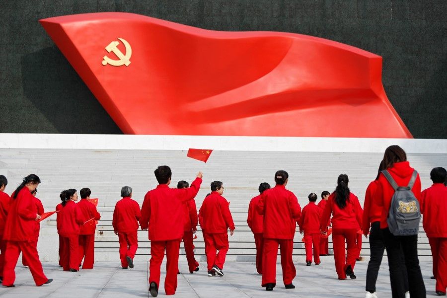 A visitor holds a Chinese flag as she and the others walk towards an installation of the Chinese Communist Party flag, at the Museum of the Communist Party of China in Beijing, China, 13 October 2022. (Florence Lo/Reuters)