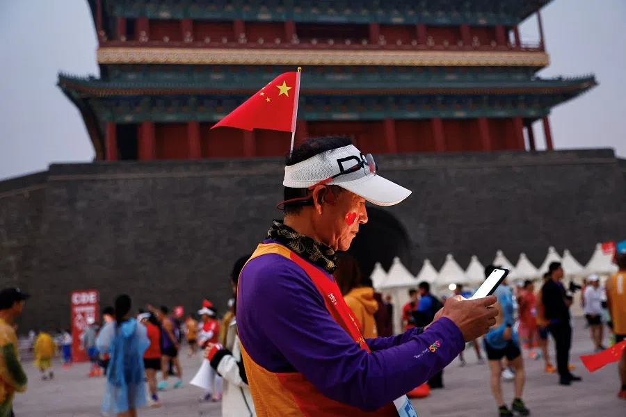 A participant wearing a hat with a national flag waits before the Beijing Marathon, at Tiananmen Square in Beijing, China, on 29 October 2023. (Tingshu Wang/Reuters)