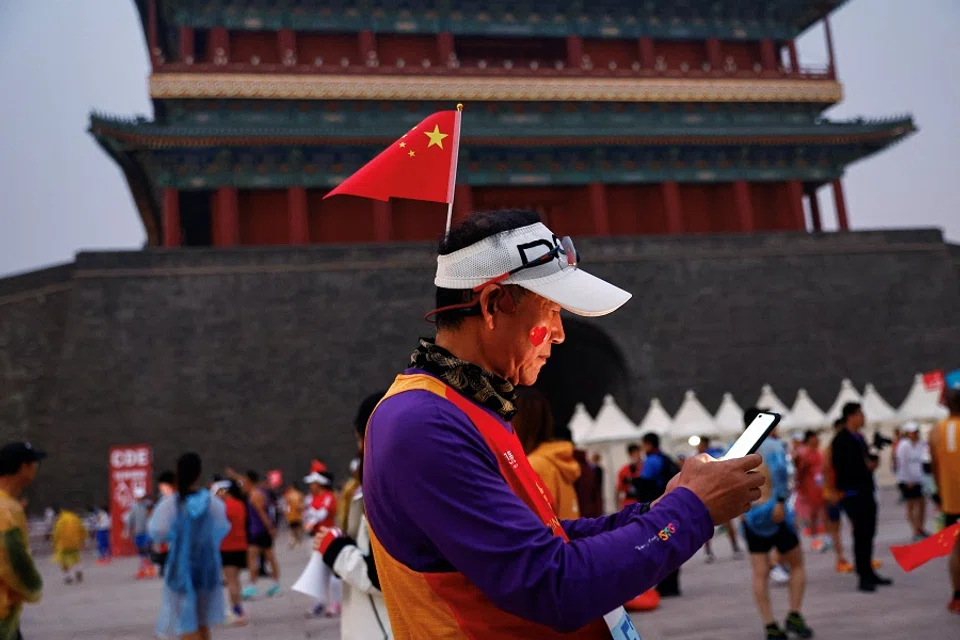 A participant wearing a hat with a national flag waits before the Beijing Marathon, at Tiananmen Square in Beijing, China, on 29 October 2023. (Tingshu Wang/Reuters)