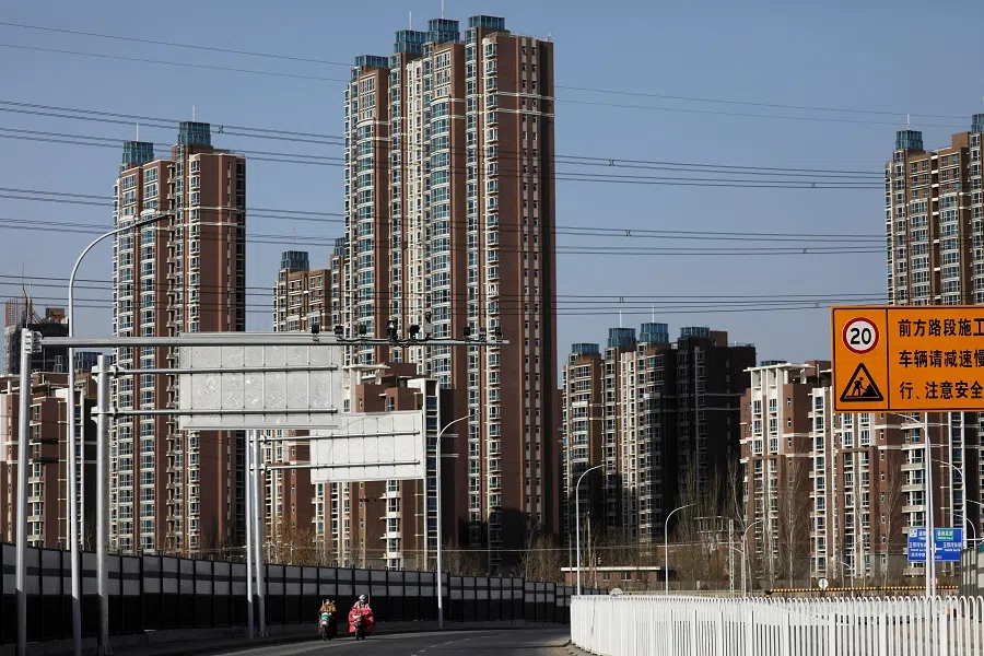 People ride scooters past residential buildings in Beijing, China, 13 January 2021. (Tingshu Wang/File Photo/Reuters)