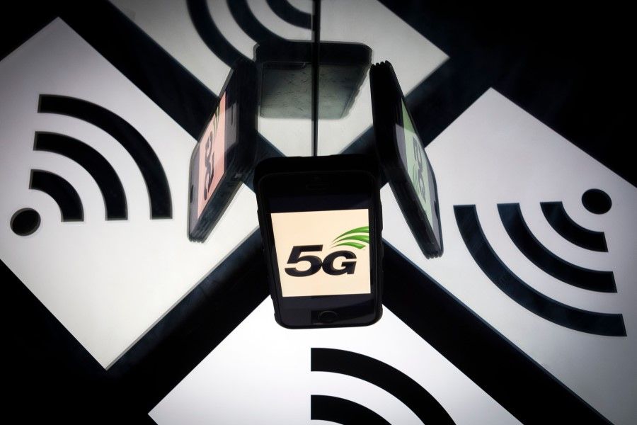 This illustration picture taken on 17 February 2019 shows the 5G wireless technology logo displayed on a smartphone and a wireless signal sign. (Lionel Bonaventure/AFP)