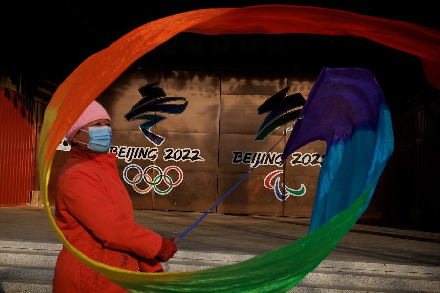 A woman flies a ribbon near the logos of the Beijing 2022 Olympic and Paralympic Games in a park in Beijing, China, 8 December 2021. (Thomas Peter/File Photo/Reuters)