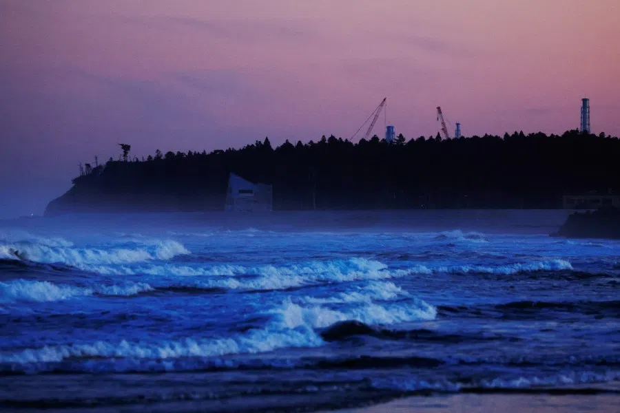 Ventilation stacks and cranes at the disabled Fukushima Dai-ichi nuclear power plant are seen from a beach in Namie, about 7 km away from the power plant, in Fukushima Prefecture, Japan, 28 February 2023. (Kim Kyung-Hoon/Reuters)