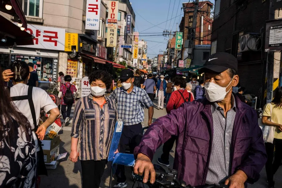 Pedestrians walk past street market stalls in Seoul on 1 October 2021. (Anthony Wallace/AFP)
