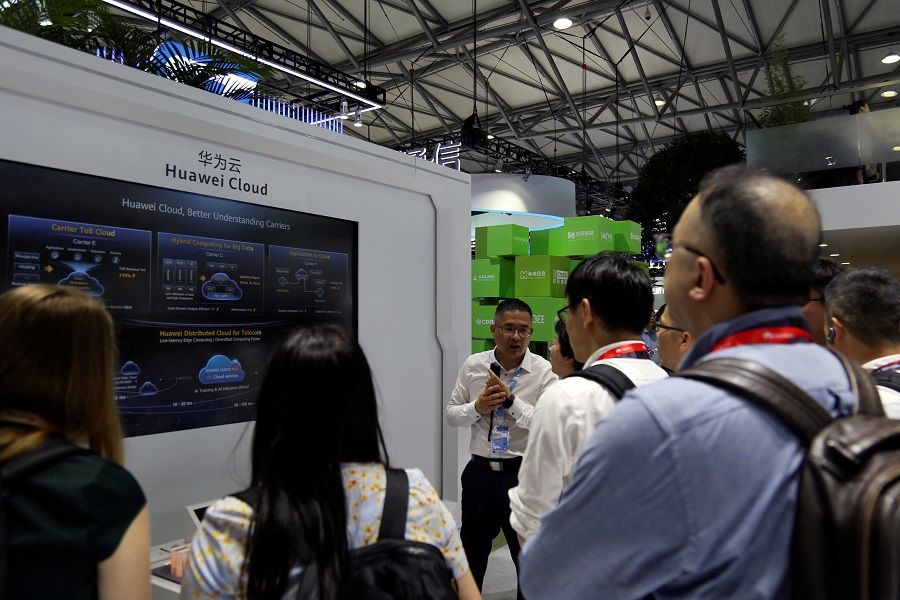 Visitors stand in front of a display on Huawei Cloud at the Huawei booth during the Mobile World Congress in Shanghai, China, on 28 June 2023. (Nicoco Chan/Reuters)
