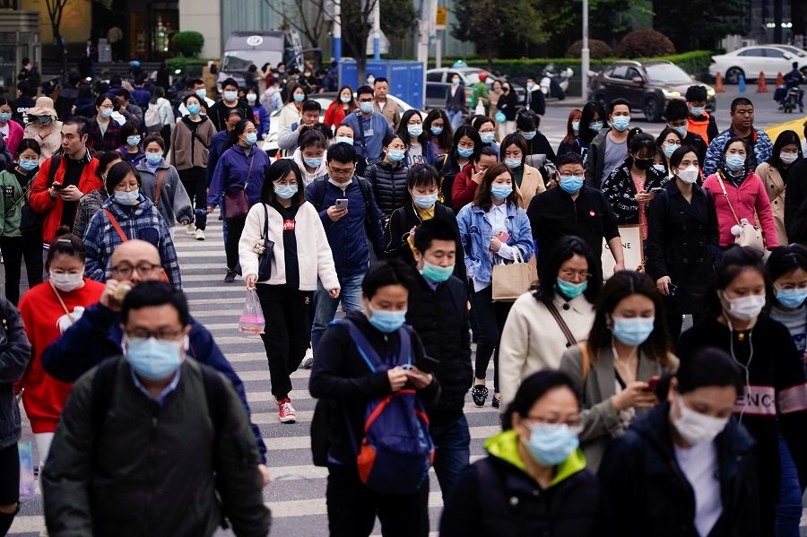 People wearing face masks walk on a street in Shanghai, China, 30 March 2021. (Aly Song/Reuters)