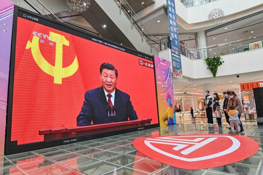 People watch a live broadcast of China's President Xi Jinping speaking during the introduction of the Communist Party of China's Politburo Standing Committee, on a screen at a shopping mall in Qingzhou in China's eastern Shandong province on 23 October 2022. (AFP)