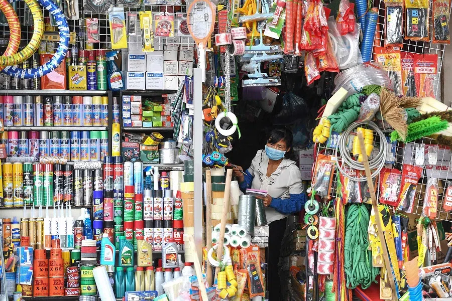 A woman wearing a protective face mask amid concerns over the spread of the Covid-19 coronavirus waits for customers at a hardware store in Hanoi on 24 February 2020. (Nhac Nguyen/AFP)