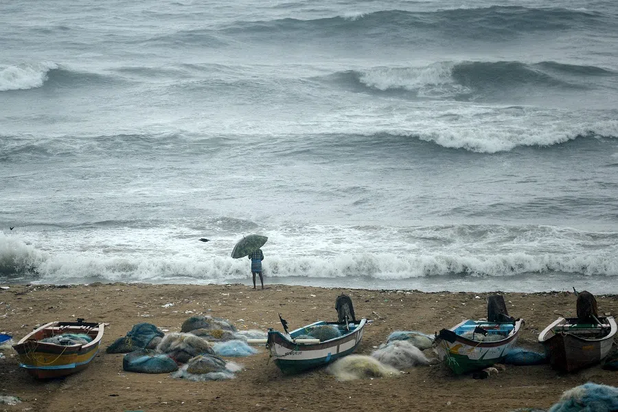 A fisherman looks out to the Indian Ocean next to fishing boats following a heavy monsoon rainfall in Chennai, India, on 9 November 2021. (Arun Sankar/AFP)