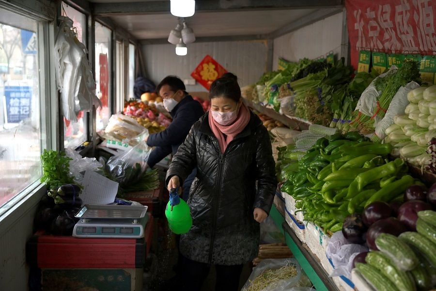 A shop owner disinfects her vegetables shop near a residential compound as the country is hit by an outbreak of the novel coronavirus in Beijing, China on 21 February 2020. (Tingshu Wang/Reuters)