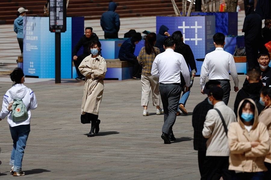 People walk on a street at a shopping area in Beijing, China, 11 April 2023. (Tingshu Wang/Reuters)