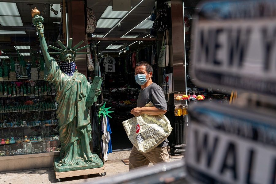 A man wearing a mask walks past a model of the Statue of Liberty at a tourist store in New York City, US, 18 July 2021. (Jeenah Moon/Reuters)